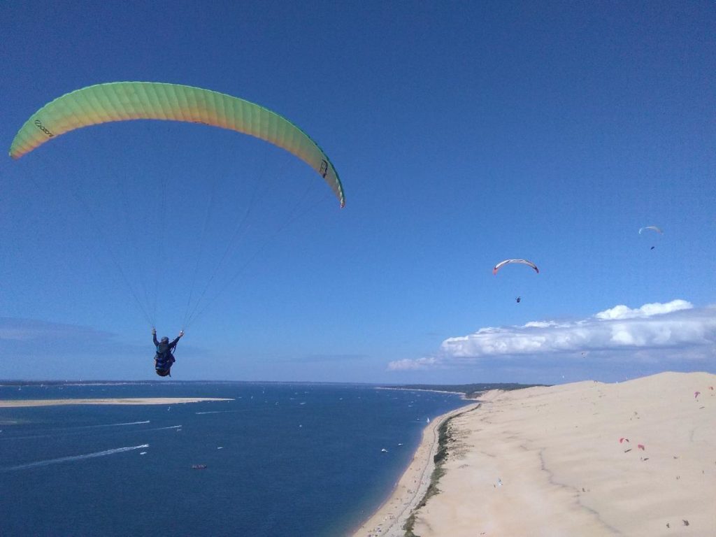 Des parapentes biplaces de la Waggas School en train de voler au-dessus de la dune du Pilat.